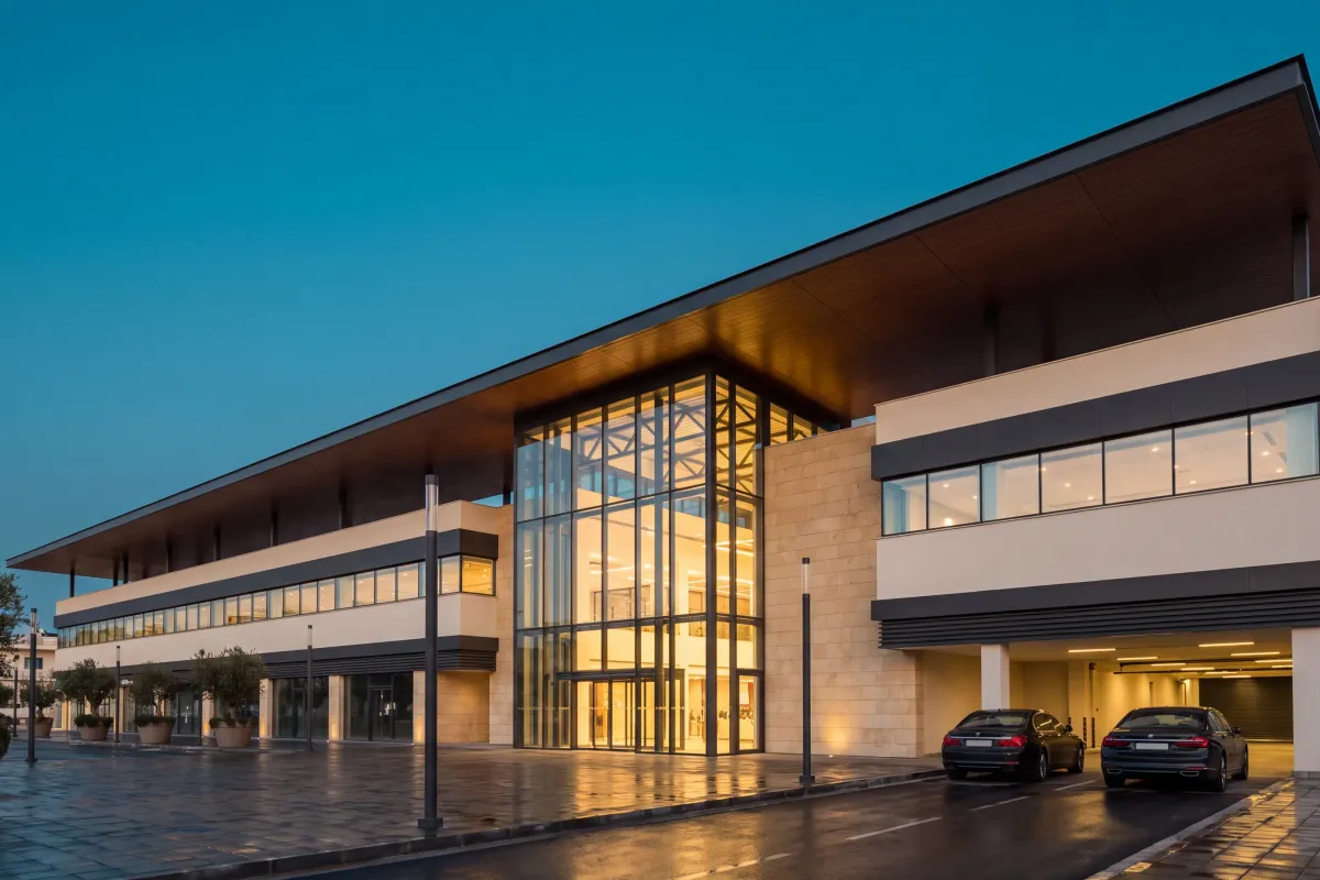 Two-storey retail and commercial building at dusk, a deep cantilevered canopy running the length of the facade over a full-height glazed atrium